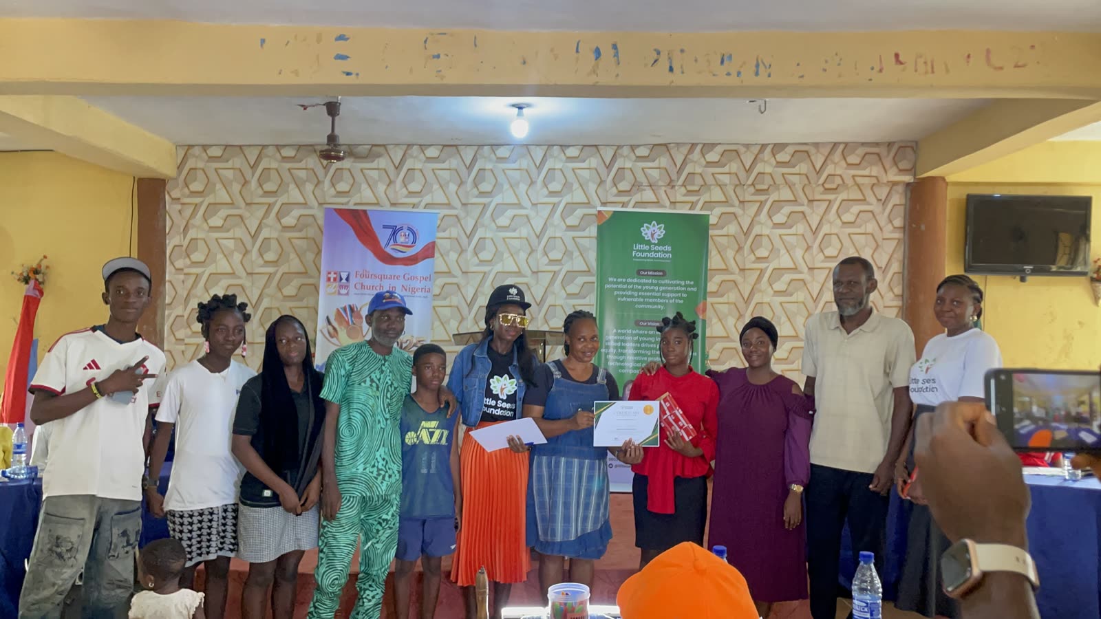A debate participant receives a certificate, joined by family and supporters